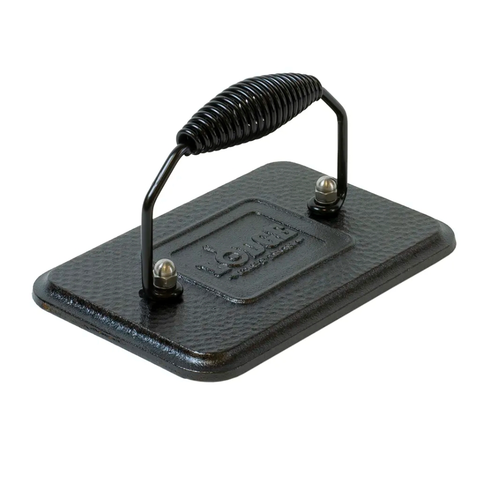 Image: A Lodge cast iron grill press with coiled wire handle and hammered finish