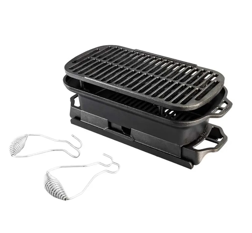 Image: A Lodge cast iron Sportsmans Grill and two stainless steel bail handles are displayed against a white background