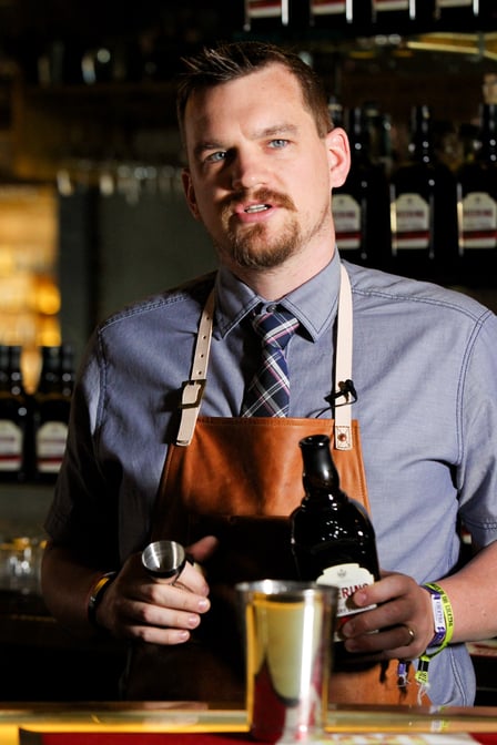 Krowne bar ambassador Troy Clarke stands behind a bar and mixes a drink